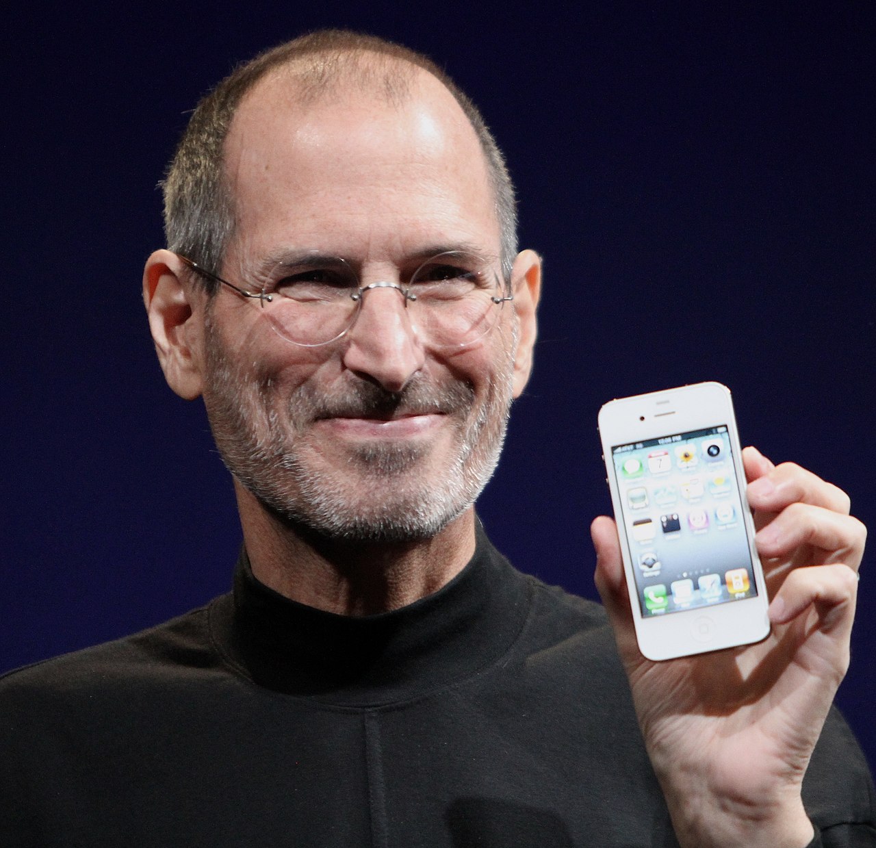Steve Jobs en un keynote, vistiendo su uniforme característico de cuello de tortuga negro y jeans
